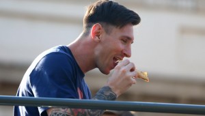 Messi, comiendo un trozo de pizza.